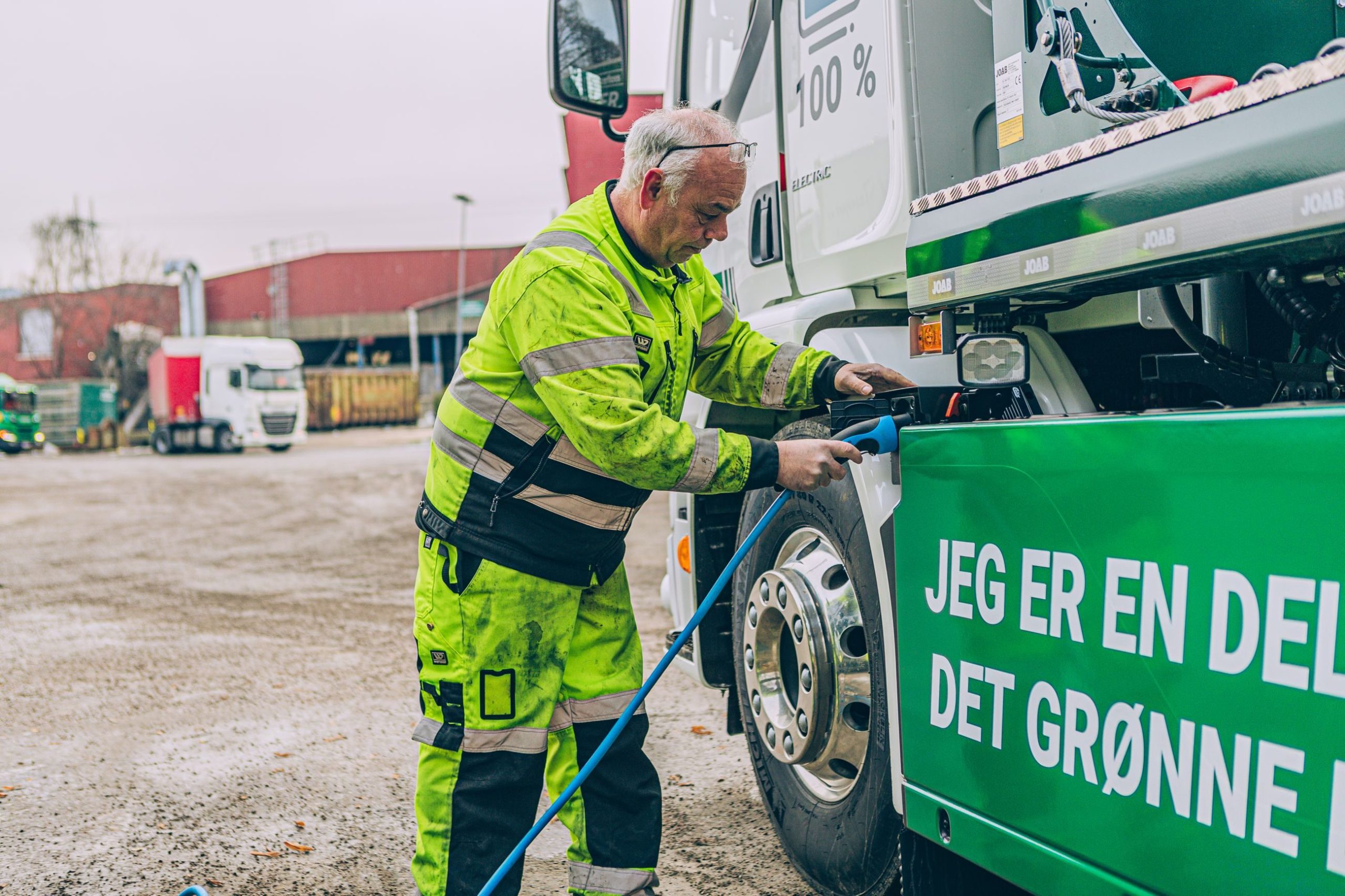 mann i arbeidsdress setter en ladekabel i en lastebil