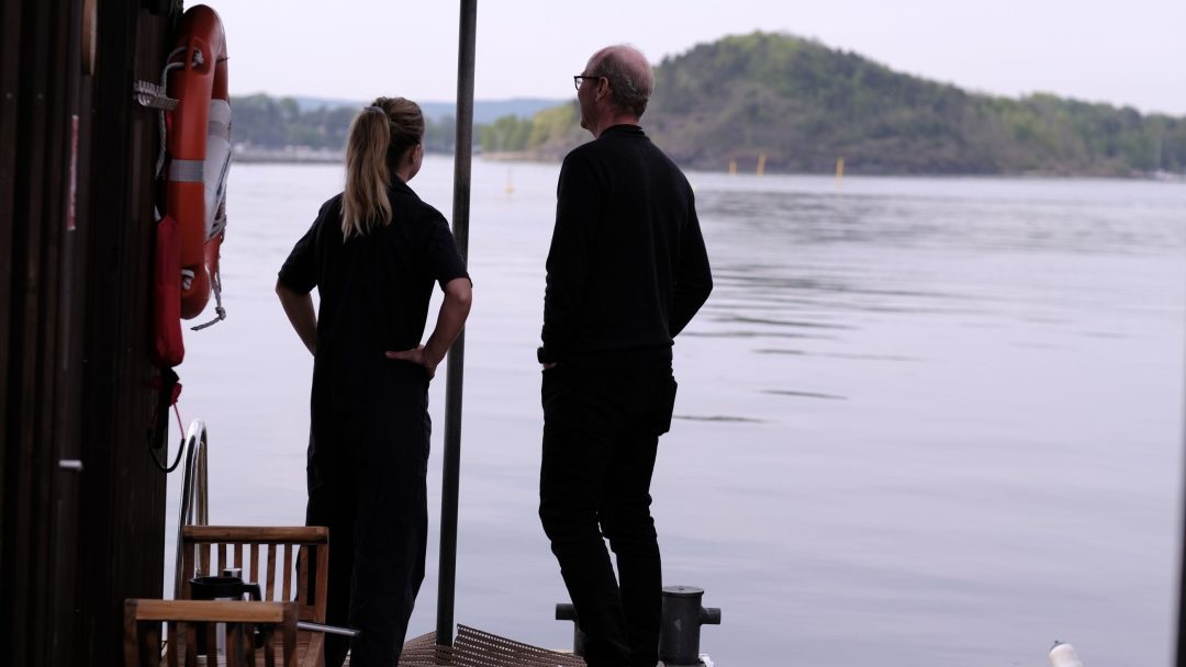 To personer som står på en brygge og nyter utsikten over vannet.
