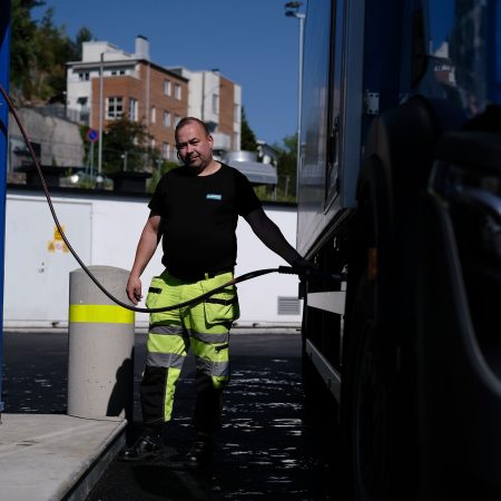 En mann fyller opp en blå lastebil på en energistasjon.