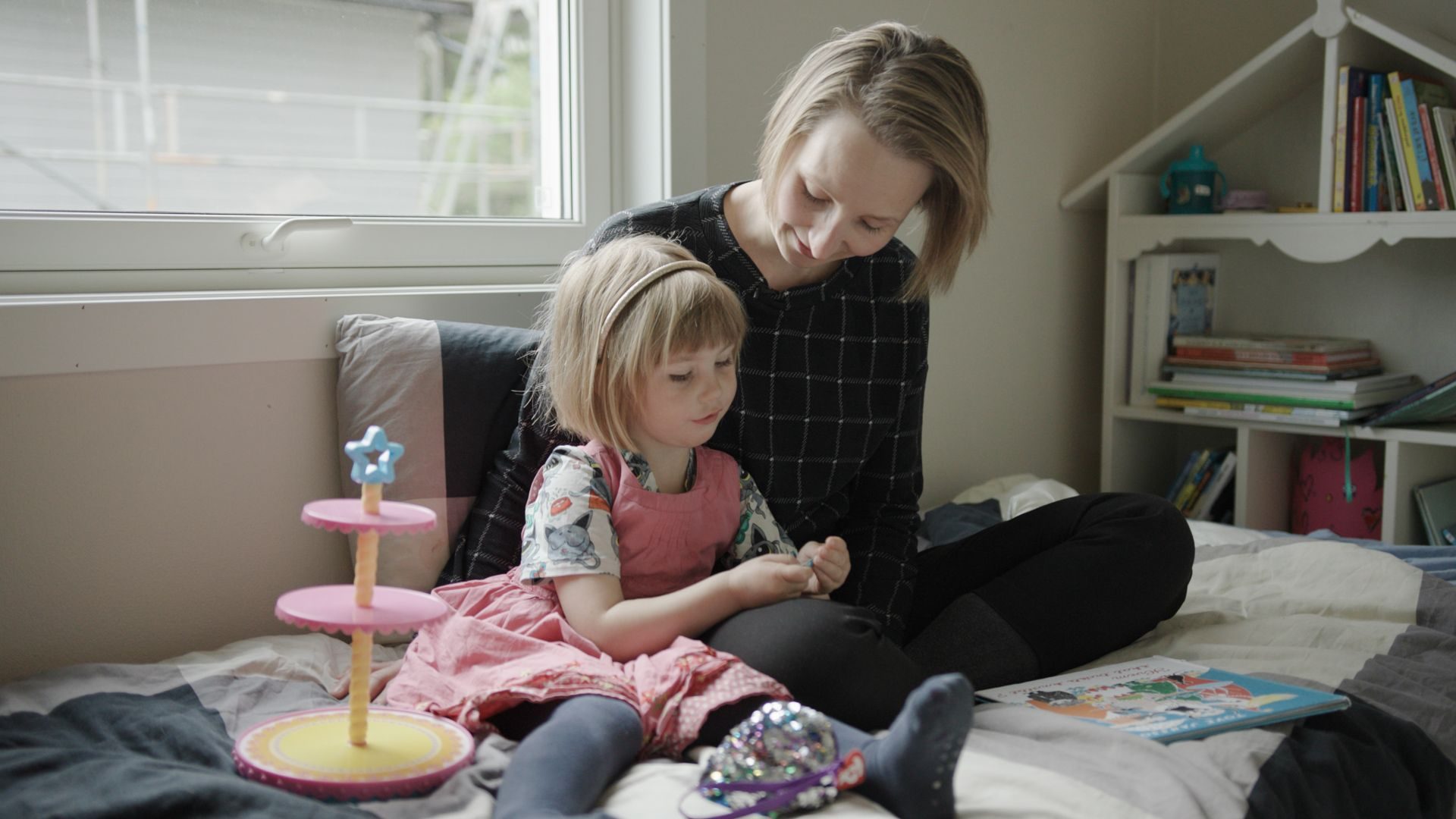 mor og datter sitter på et gulv foran et vindu