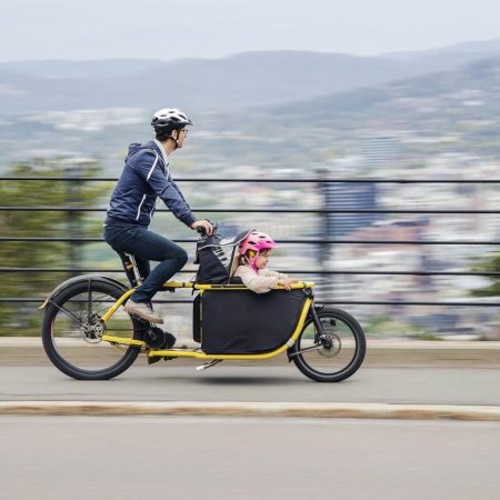 mann på sykkel med et bar i sittebag foran seg