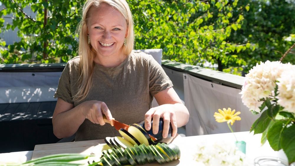 kvinne sitter ute og kutter agurk