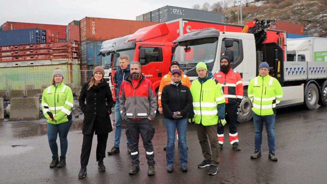 flere personer står foran parkerte lastebiler