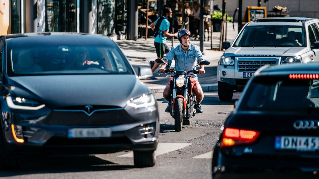 En elmotorsykkel-rytter som manøvrerer gjennom en travel gjennomfartsvei.