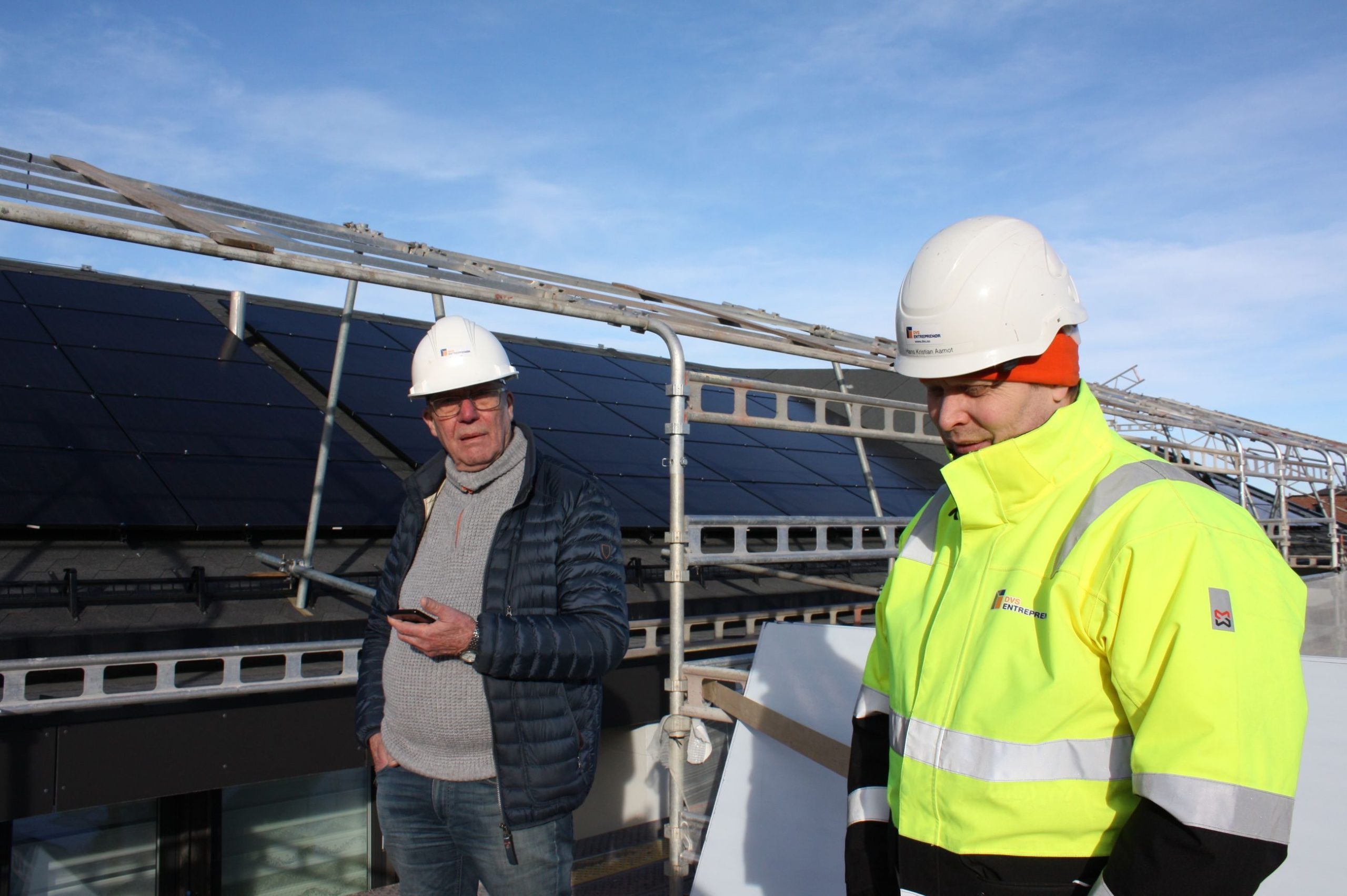 Oddvar Hansen, styreleder i Bertramjordet borettslag ser på solcellene som installeres på taket sammen med Hans Kristian Aamodt, byggeleder i DVS Entreprenører.