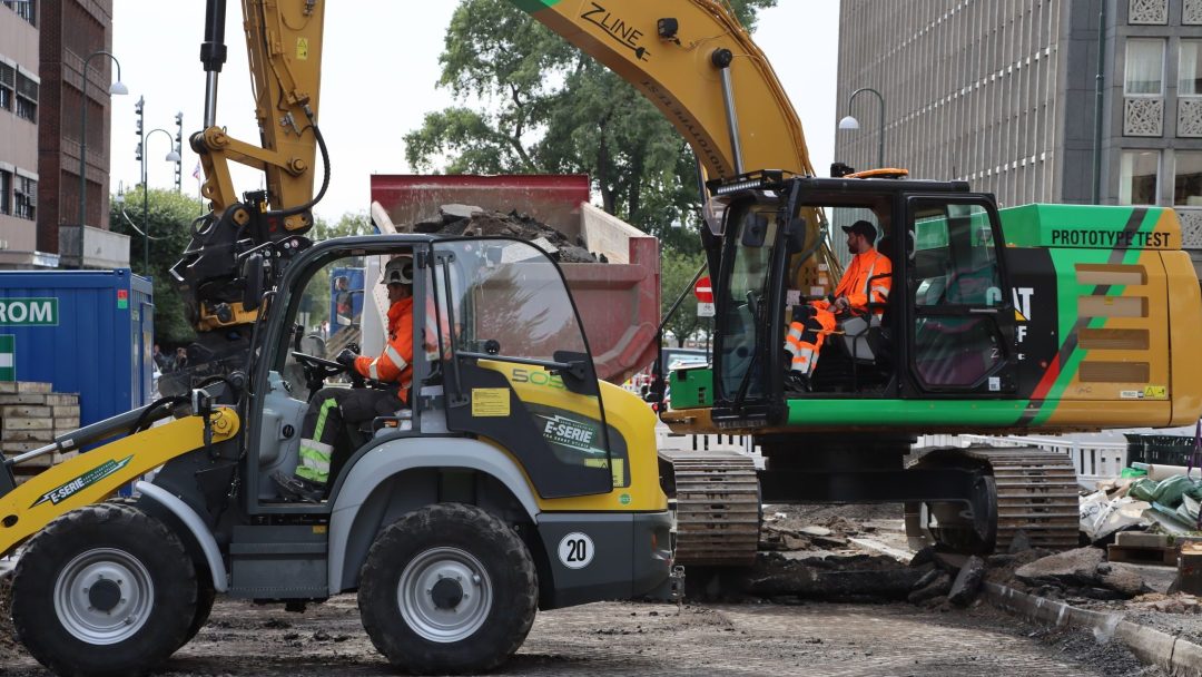 Three electric excavators and an electric wheel loader are working on the street.