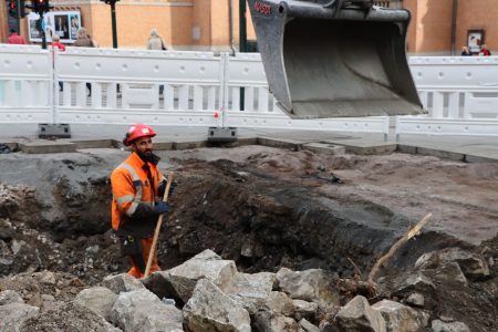 En arbeider på verdens første utslippsfrie byggeplass i Olav Vs gate i Oslo. Tre elgravemaskiner og elhjullaster er i arbeider her.