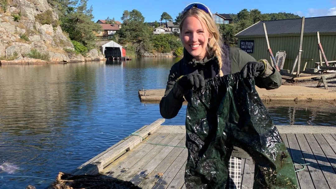 jente holder frem regnbukse som er hentet opp av vannet