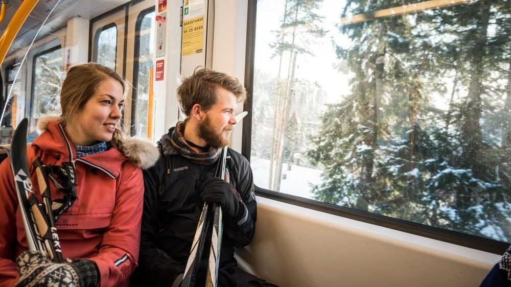 Kvinne og mann reiser kollektivt med ski