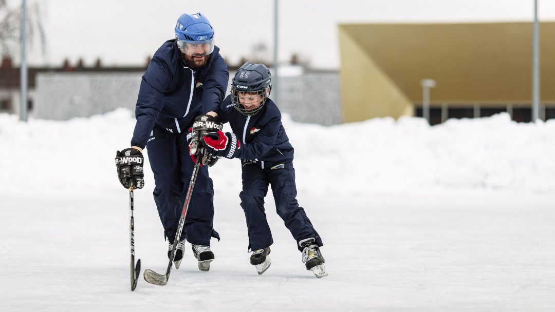 Mann og gutt spiller ishockey utendørs