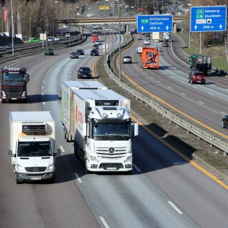 trailere, lastebiler og personbiler som kjører på en åttefelts vei