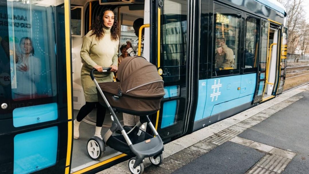 kvinne med barnevogn som går ut av en trikk