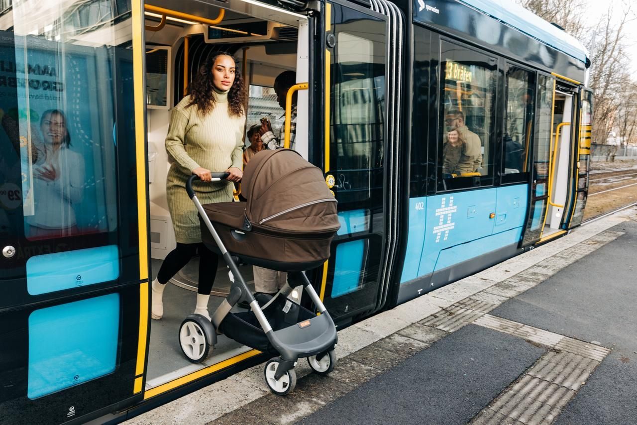 Kvinne med barnevogn på vei ut av trikken. Flere kollektivreisene er nødvendig for å nå klimamålene