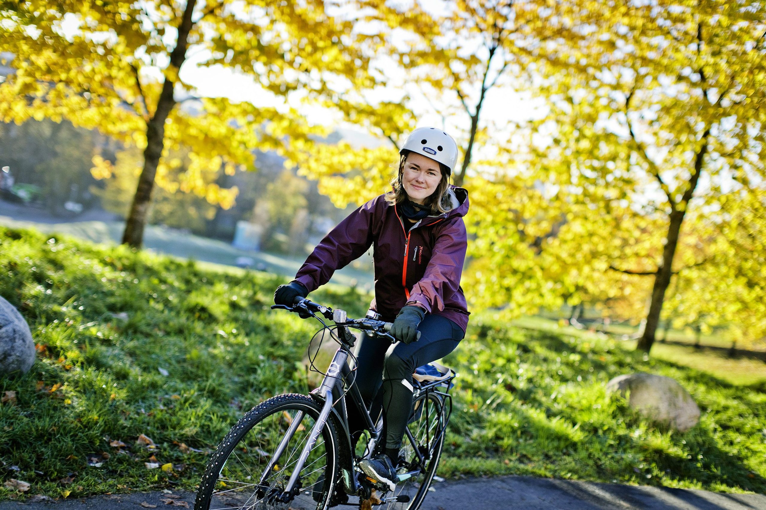 Torunn Brånå sykler på foran trær på Sagene.