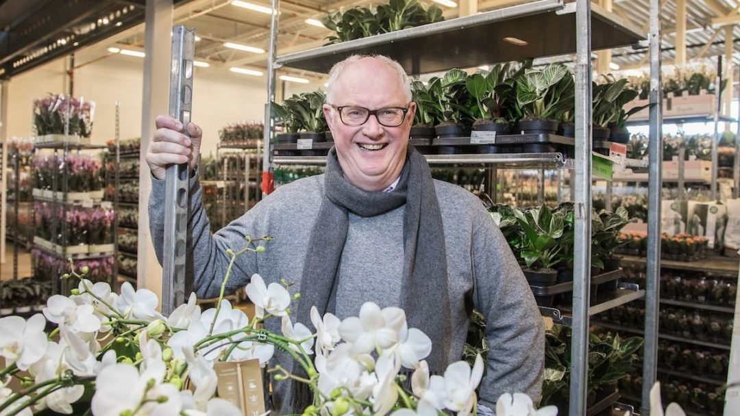 Eier av Mester grønn foran blomsterkranser.