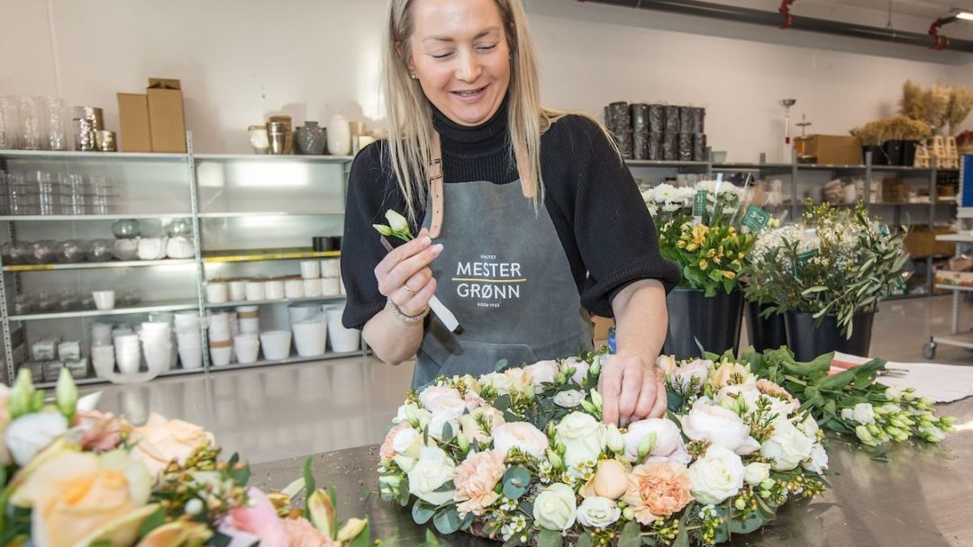 Blomsterdekoratør setter sammen en sorgkrans til grav.