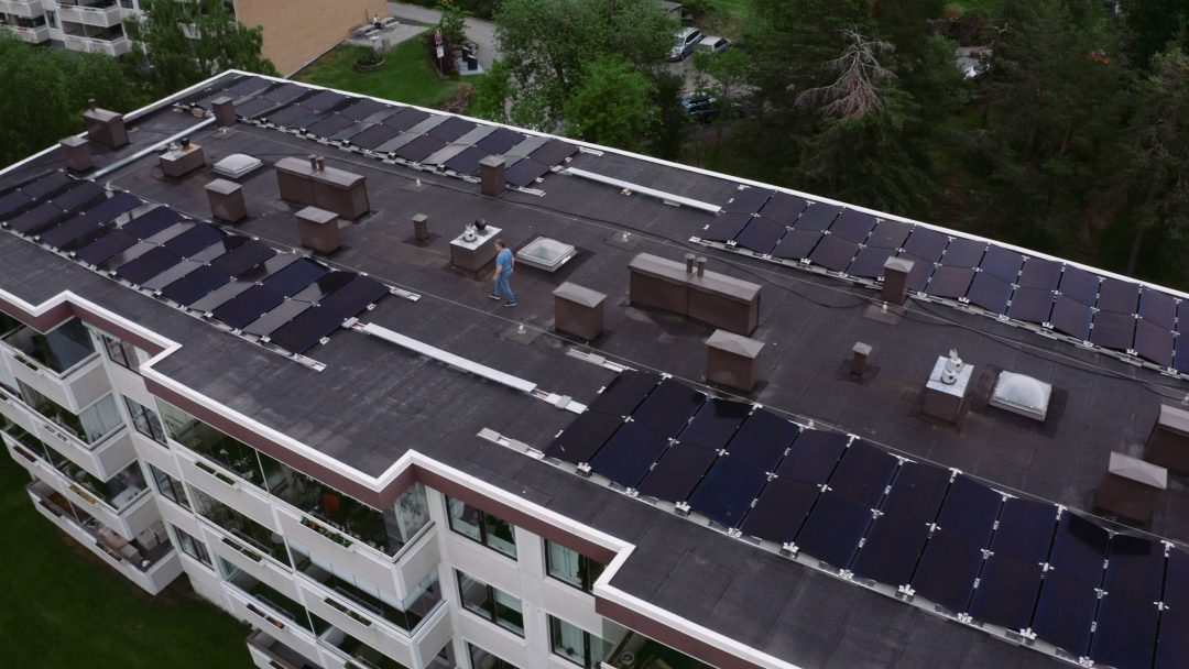 Dronebilde av solceller på taket til boligblokk.