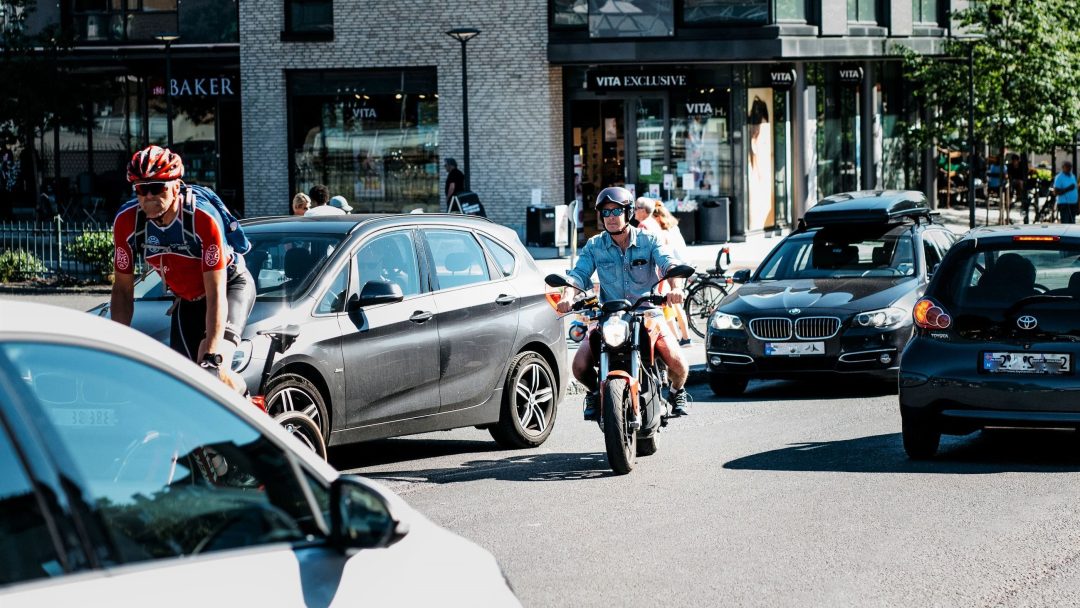 En mann som kjører en elmotorsykkel i en bygate.