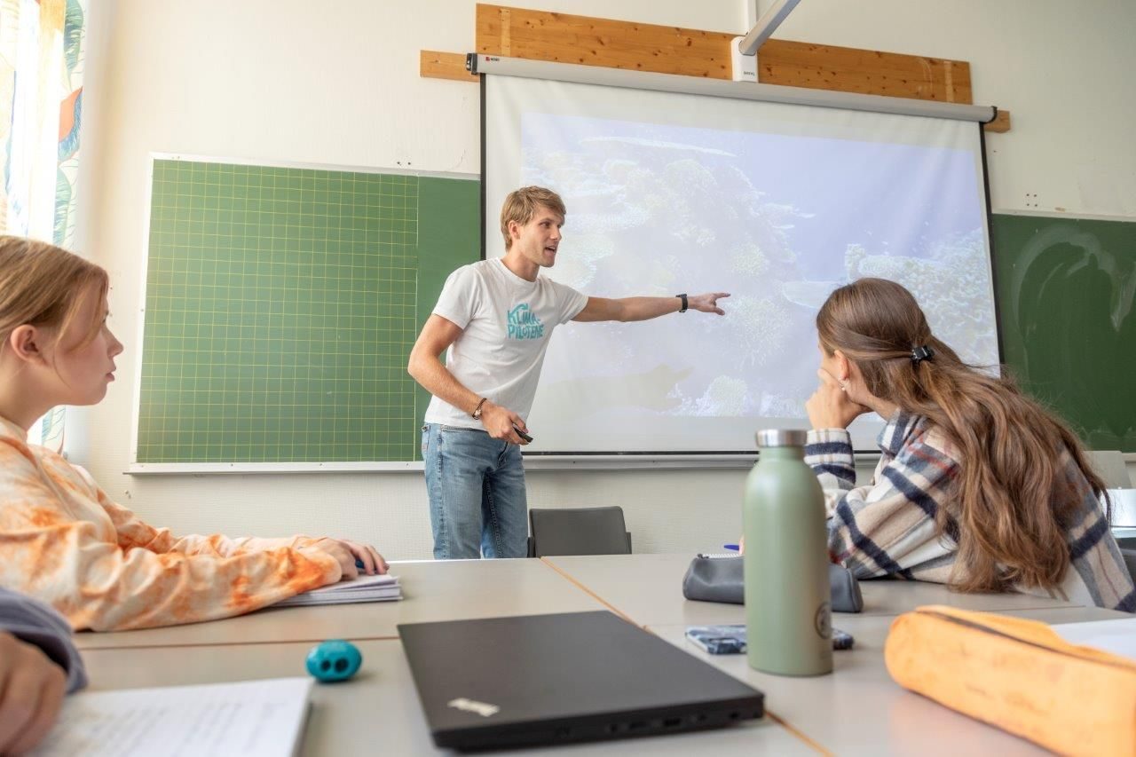 En lærer gir et klimaforedrag til elever i et klasserom.