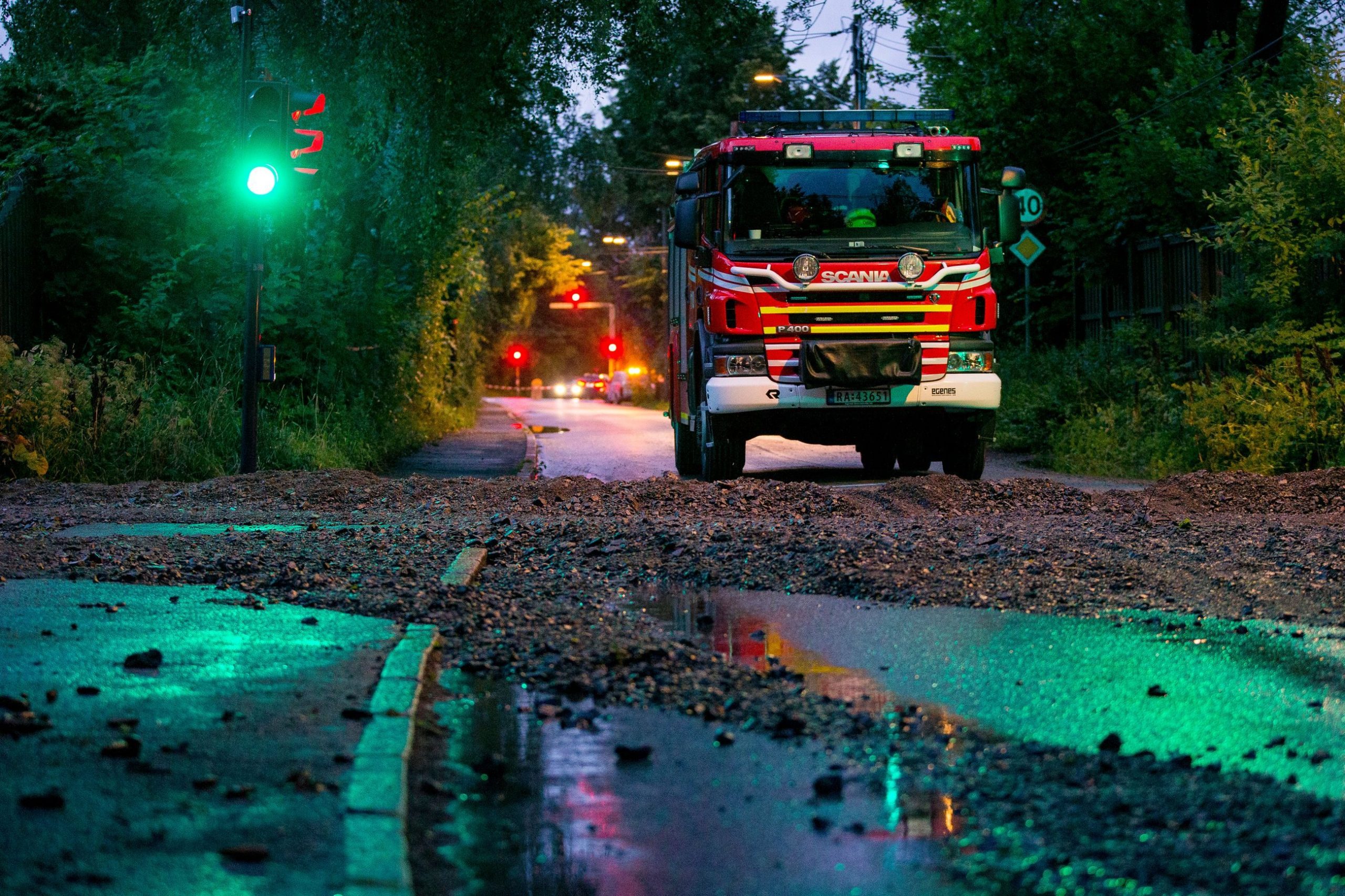 En lastebil kjører nedover en gjørmete vei om natten.