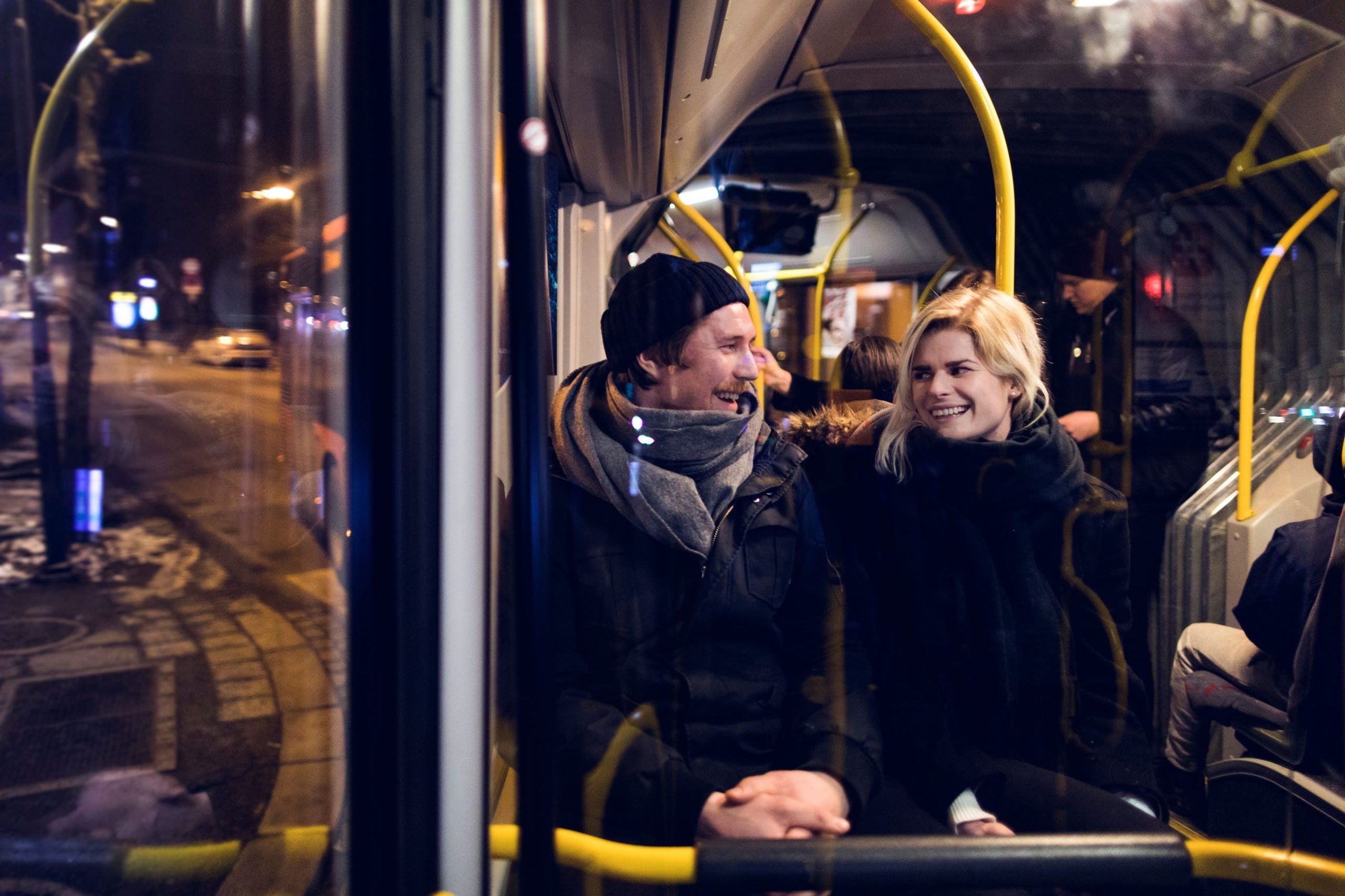 En mann og en kvinne sitter på en buss om natten.