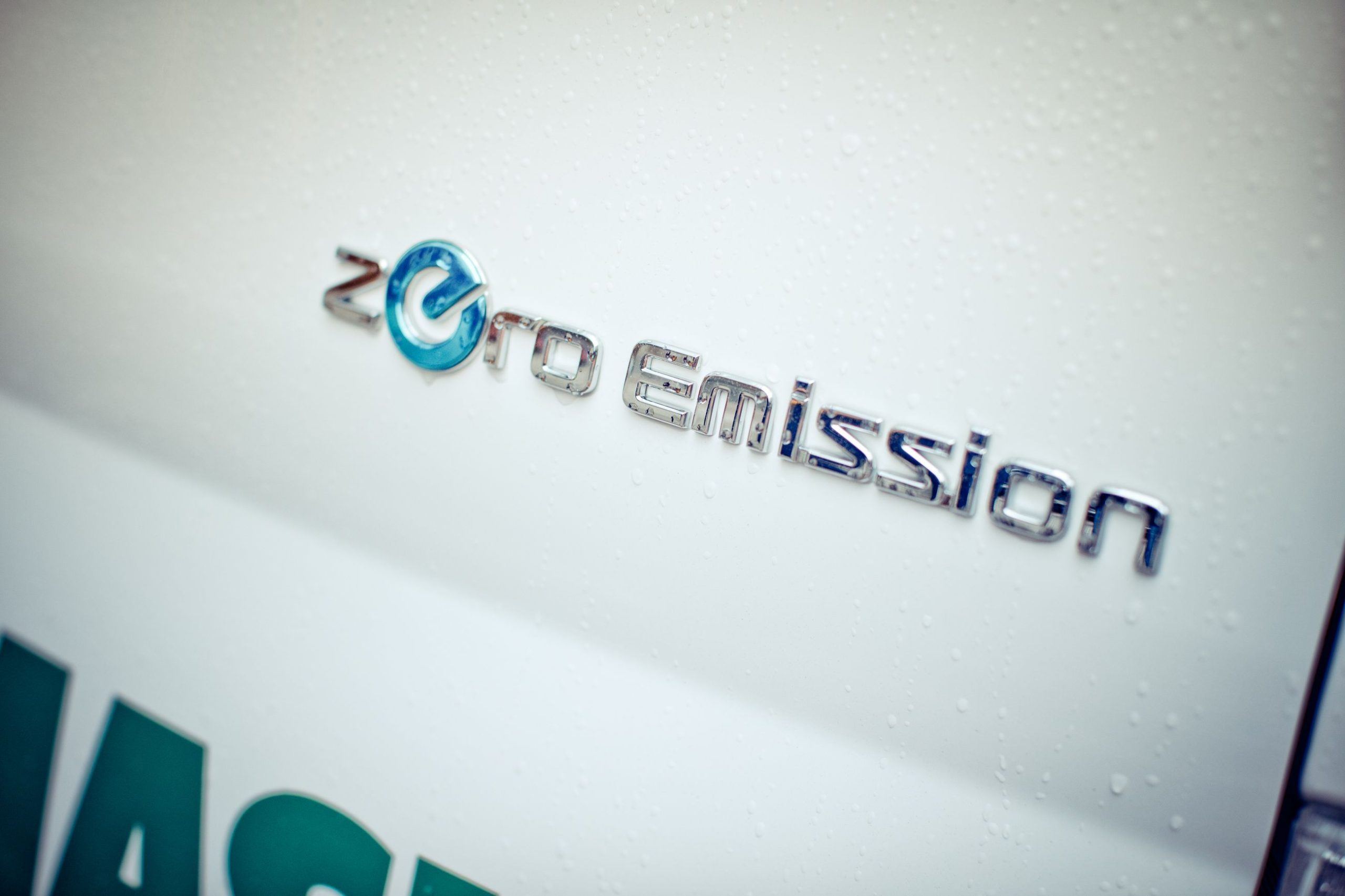 Zero emission skrevet i sølvbokstaver på en hvit bil, nærbilde.