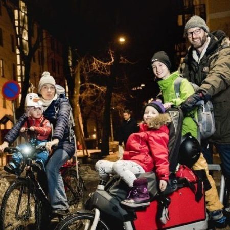 family of four children and two adults on bikes in the dark Oslo morning
