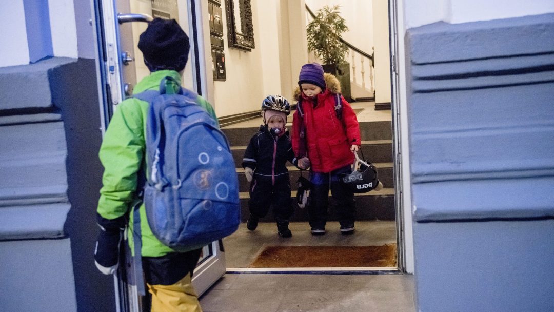 Three children on their way out of the front door of an apartment in Vika.