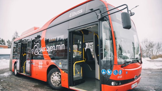 En rød el-leddbuss. På siden står det jeg el-sker byen min.