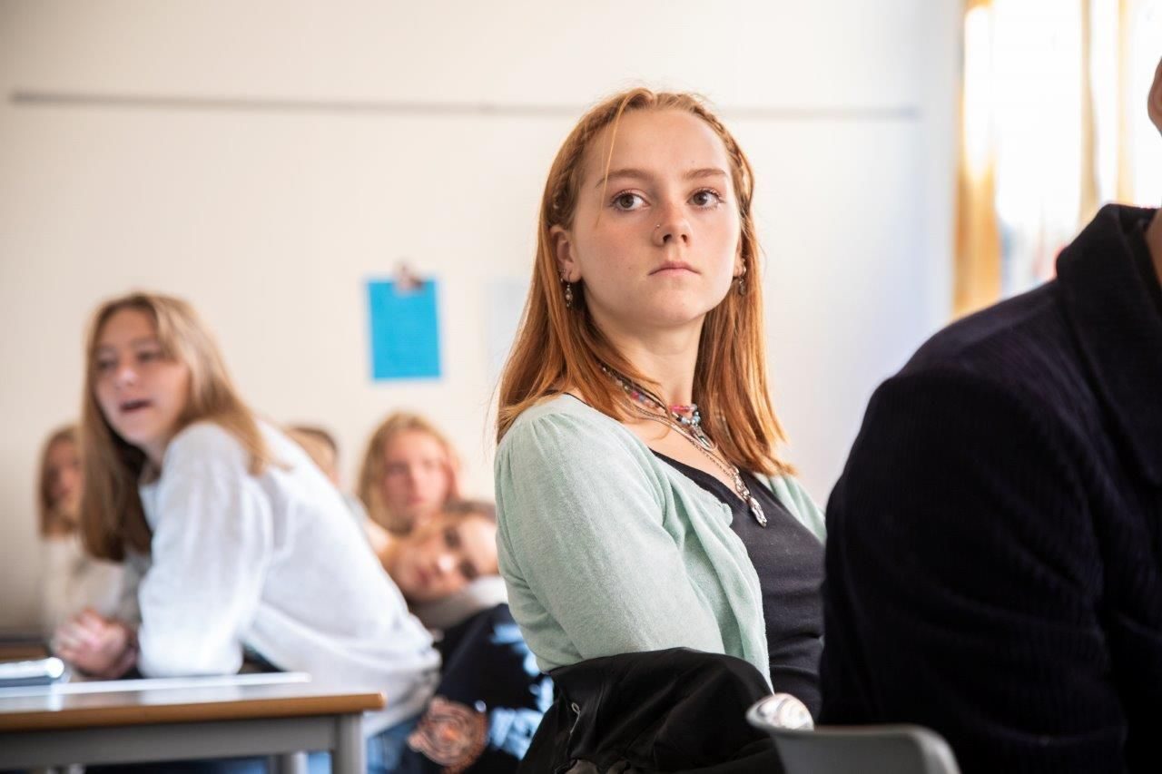 En gruppe mennesker som deltar på klimaforedrag i et klasserom.