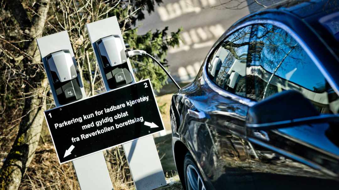 Bil ved siden av skilt om parkering for ladbare kjøretøy