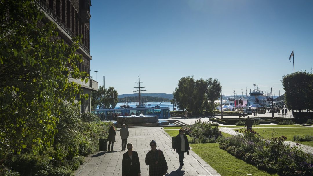 mennesker spaserer i Rådhusparken i solskinn