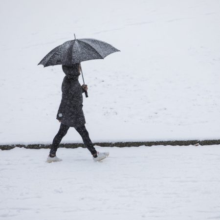 En person som går med paraply. Snø på bakken
