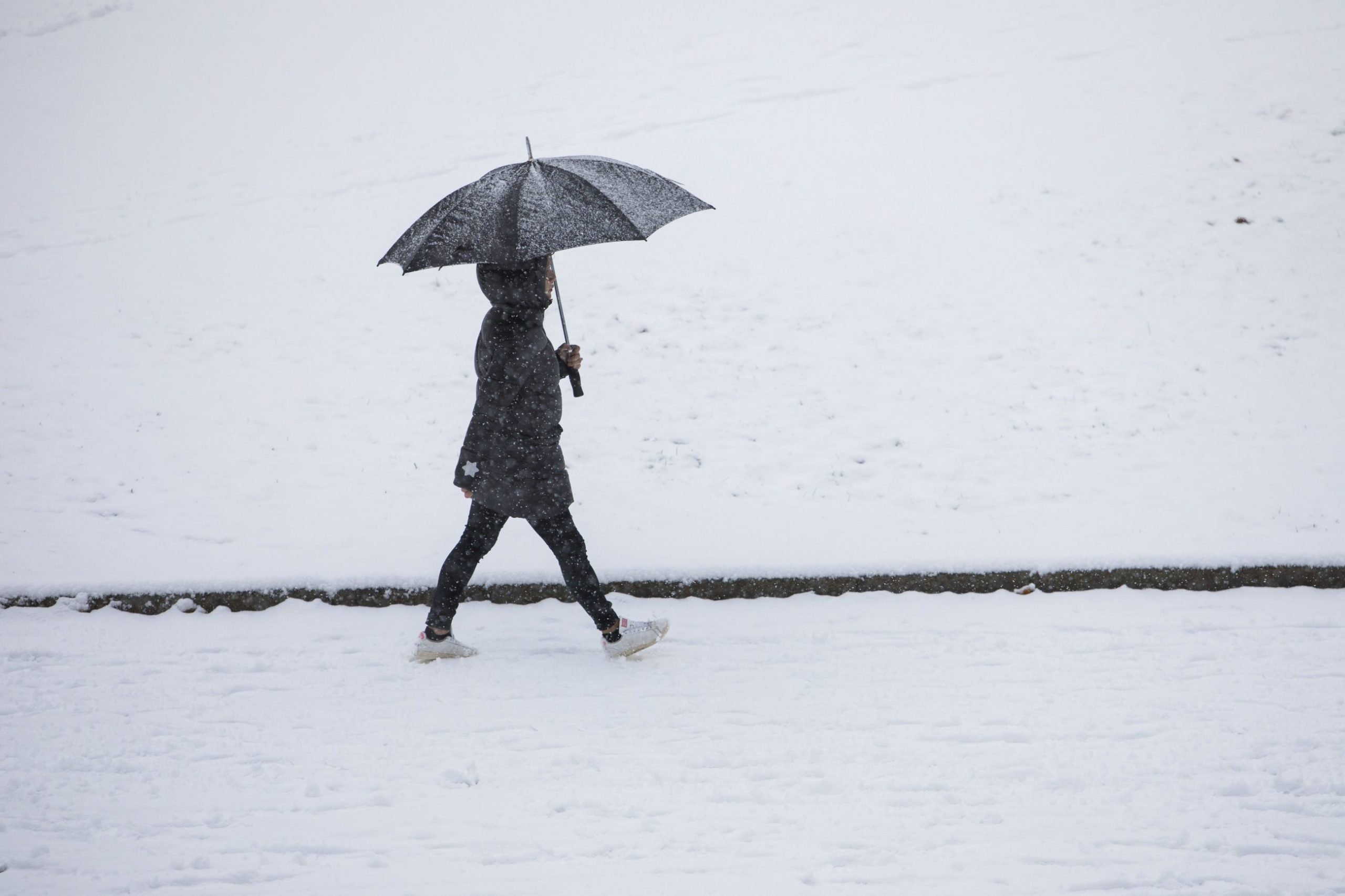 En person som går med paraply. Snø på bakken