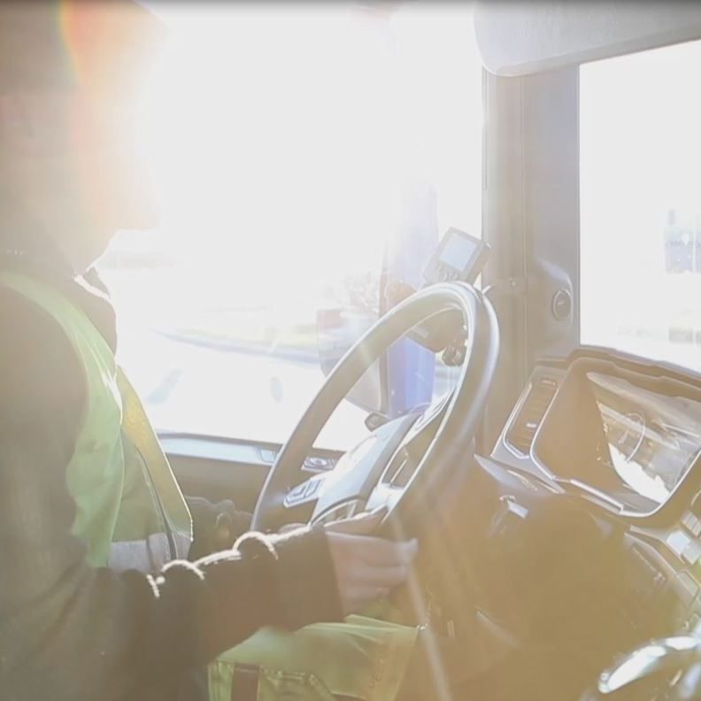 lastebilsjåfør i førerhuset med sola som skinner gjennom vinduet.