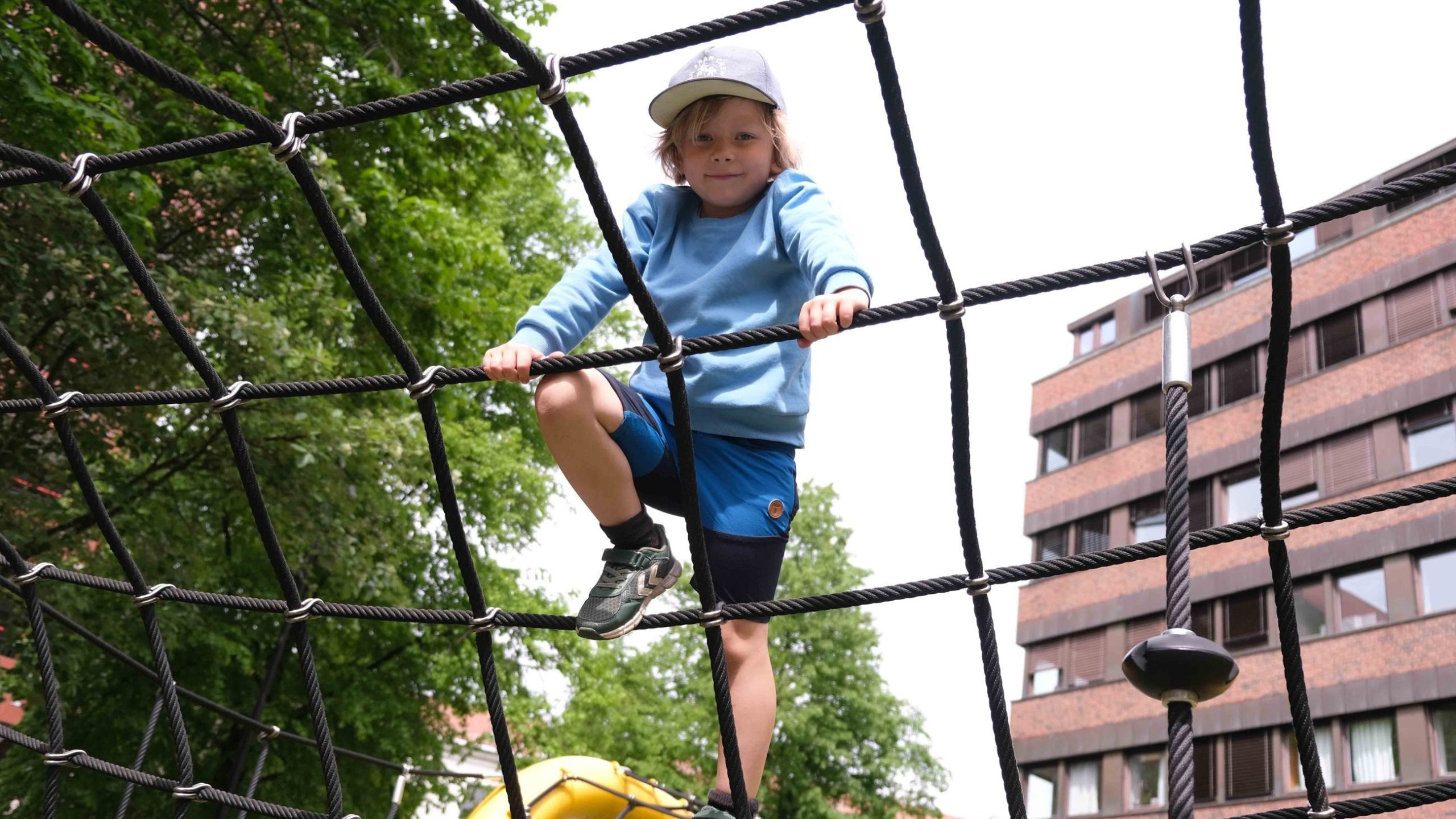 Gustav står i klatrestativet og smiler til kameraet.