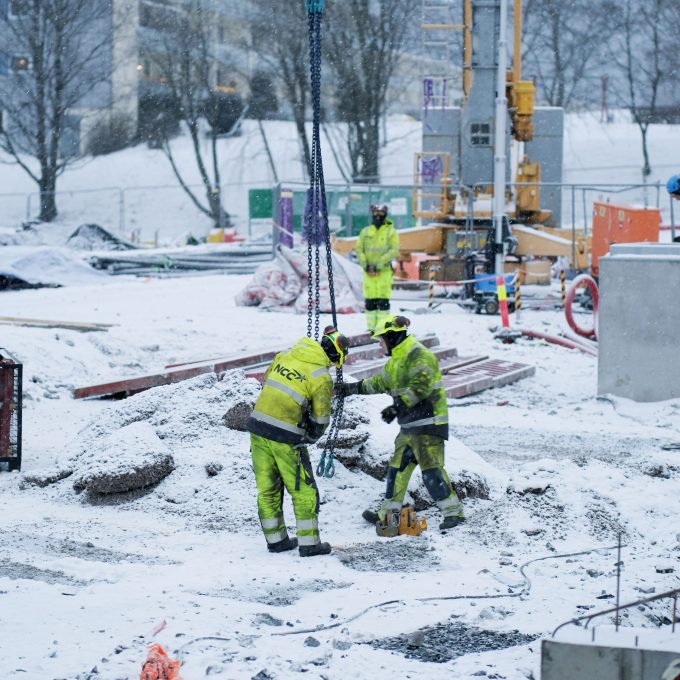 Bygningsarbeidere som jobber på en utslippsfri byggeplass i snøen.