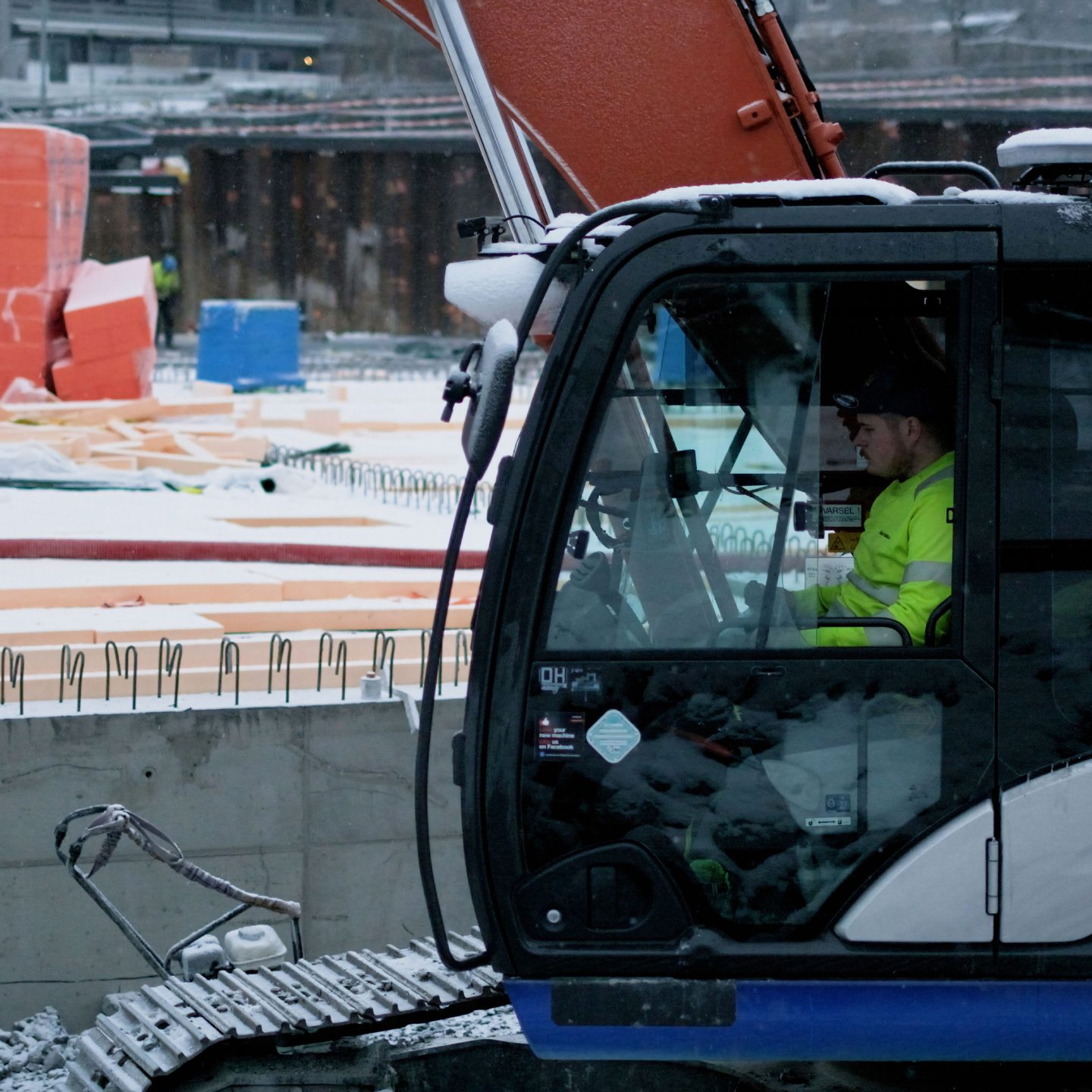 En bygningsarbeider sitter i en utslippsfri gravemaskin på byggeplassen. The operator of an eledtric excabator.