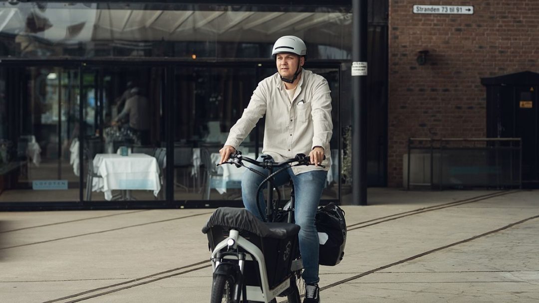 Mann som sykler på elektrisk lastesykkel i sentrum