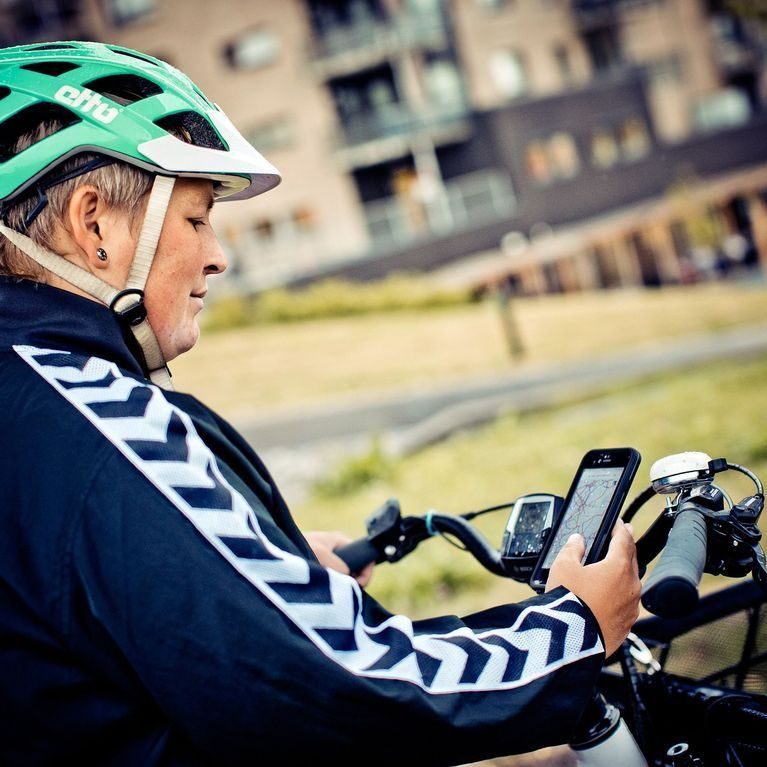 Kvinne med grønn sykkelhjelm ser på sykkelkartet på mobilen