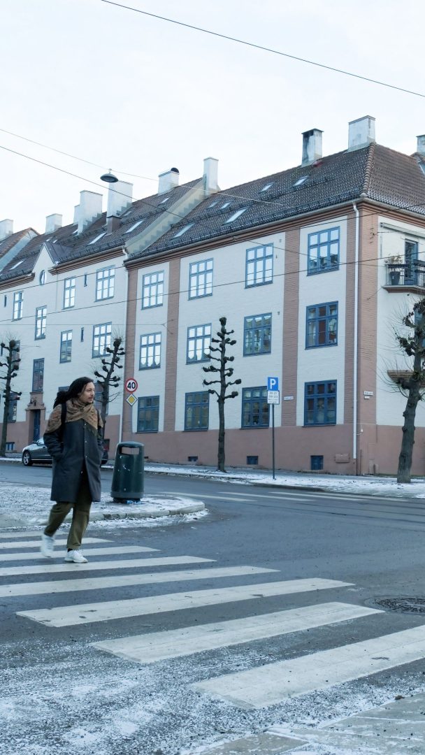 En person som skal på jobb krysser gaten ved et sebraovergang i en europeisk by om vinteren.