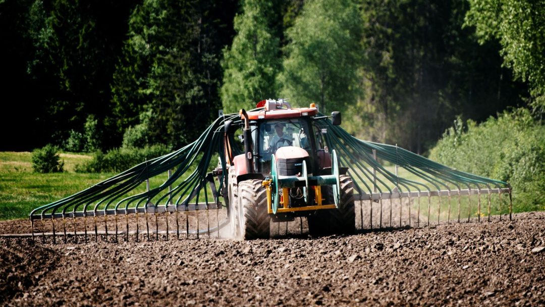 Traktor sprer gjødsel på jorde