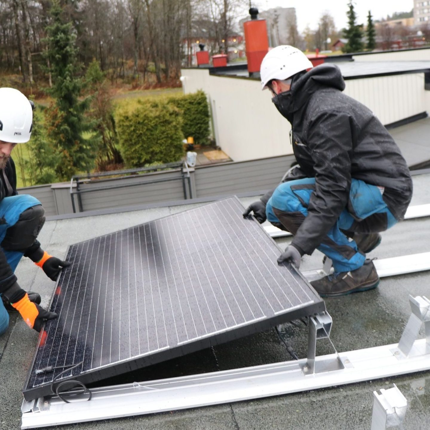 to menn monterer solceller på taket av en bolig