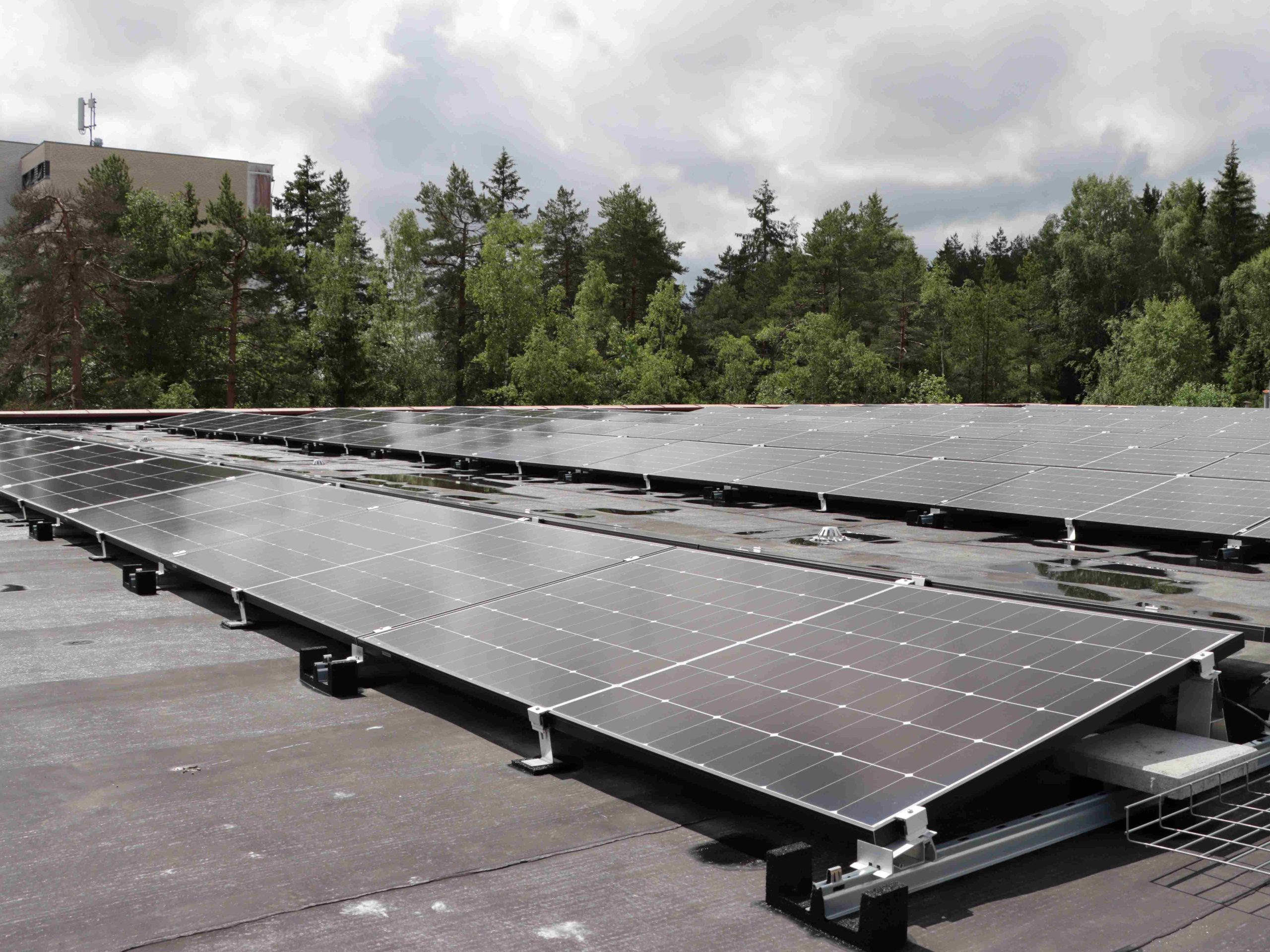 solceller som kan produsere solenergi på et garasjetak med trær og himmel bak