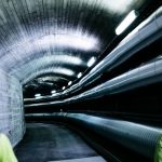 fjernvarmestyring: to arbeidere går gjennom en opplyst tunnel med tre store rør for fjernvarme