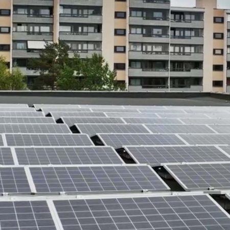 Solcellepaneler på et hustak med leilighetsbygg i bakgrunnen, viser Oslos satsing på bærekraft gjennom KlimaOslo-tiltak under overskyet himmel.