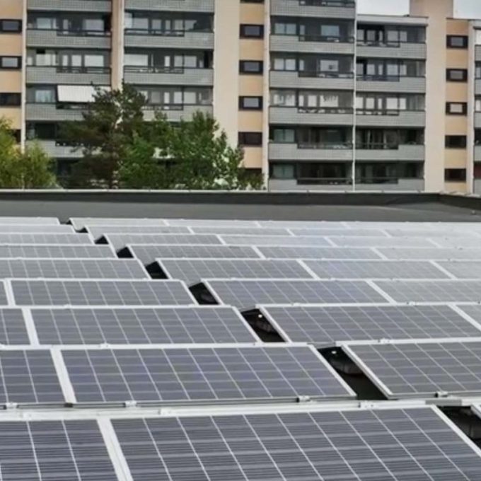 Solcellepaneler på et hustak med leilighetsbygg i bakgrunnen, viser Oslos satsing på bærekraft gjennom KlimaOslo-tiltak under overskyet himmel.