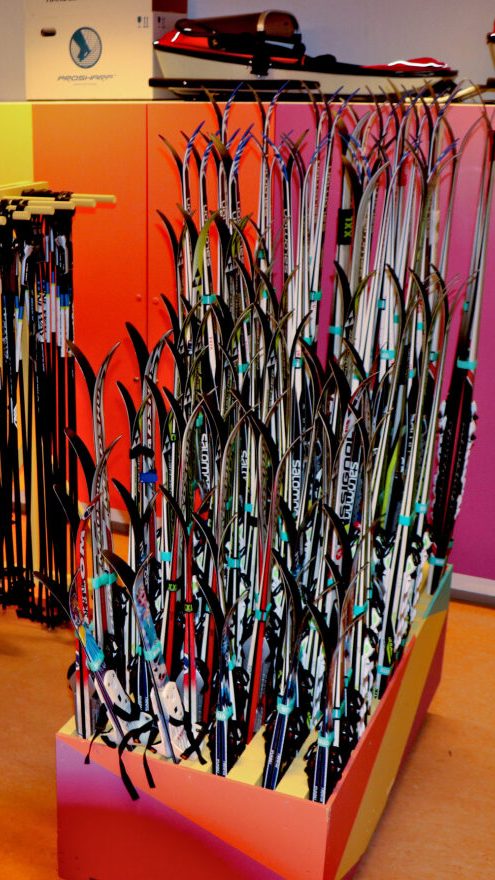 Et rom med stativer av diverse skistaver og ski er pent organisert mot fargerike vegger, og legemliggjør mindre for klima-etosen.