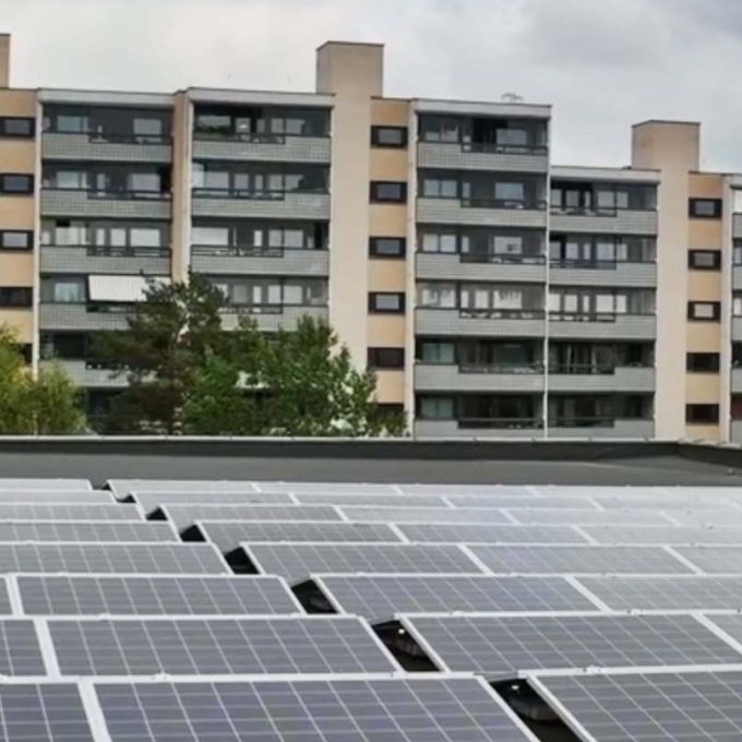 Solcellepaneler på et hustak med leilighetsbygg i bakgrunnen, viser Oslos satsing på bærekraft gjennom KlimaOslo-tiltak under overskyet himmel.