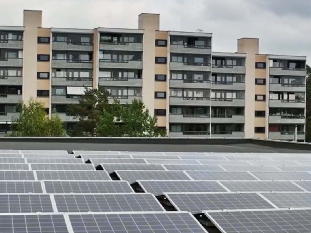 Solcellepaneler på et hustak med leilighetsbygg i bakgrunnen, viser Oslos satsing på bærekraft gjennom KlimaOslo-tiltak under overskyet himmel.